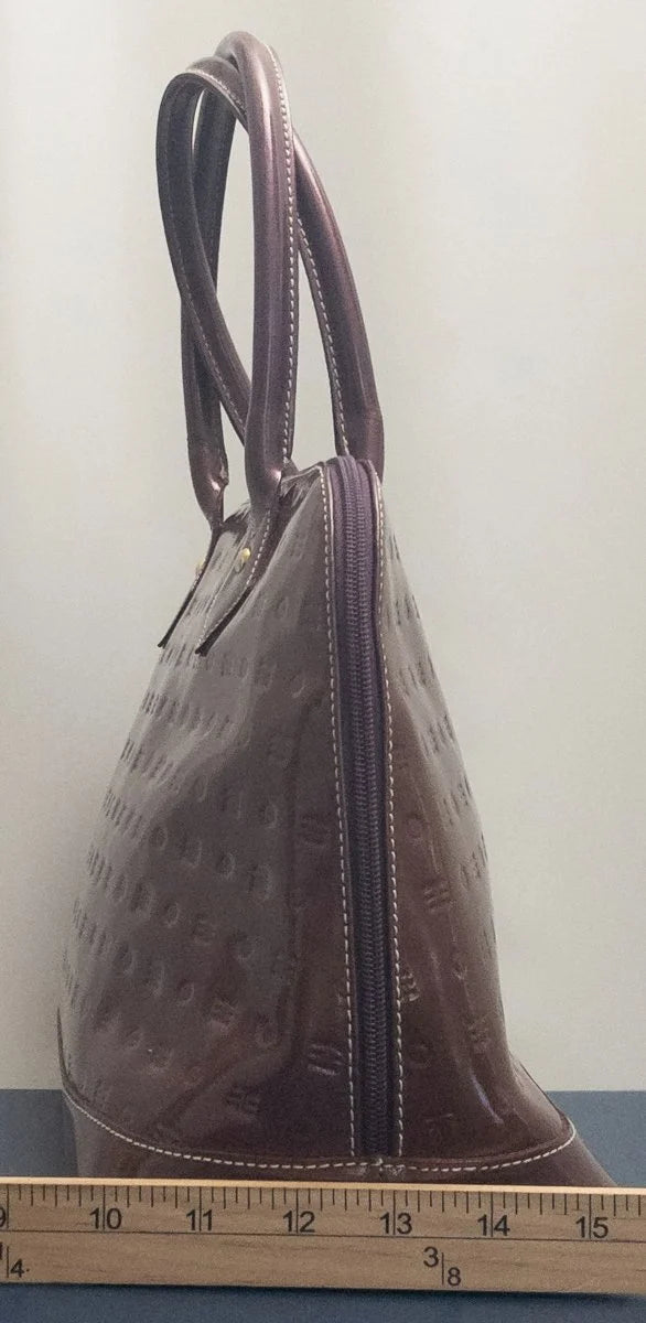 A brown textured leather handbag with double top handles and a zippered closure, shown next to a wooden ruler for scale against a plain light background.