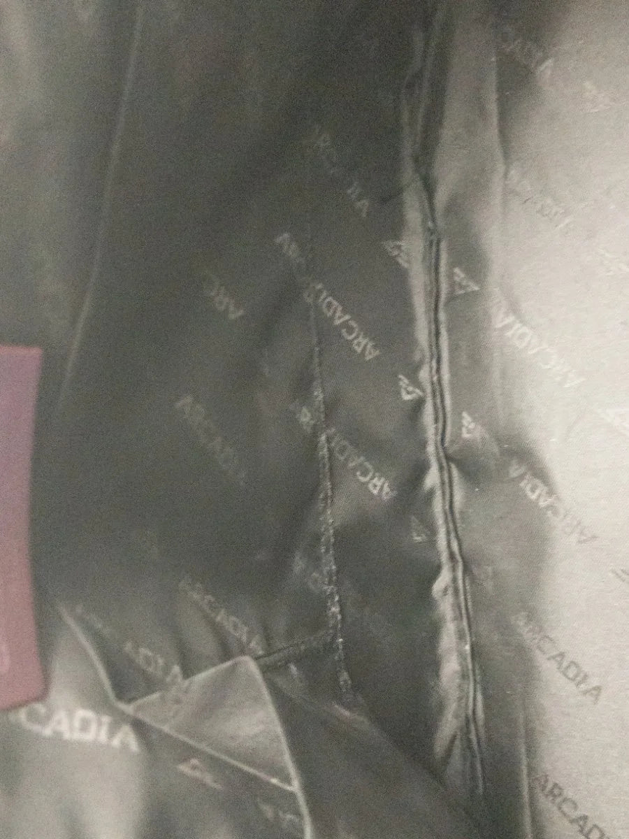 Close-up of the interior lining of a dark gray Arcadia garment, showing the brand name 'ARCADIA' repeated in light gray on the fabric.